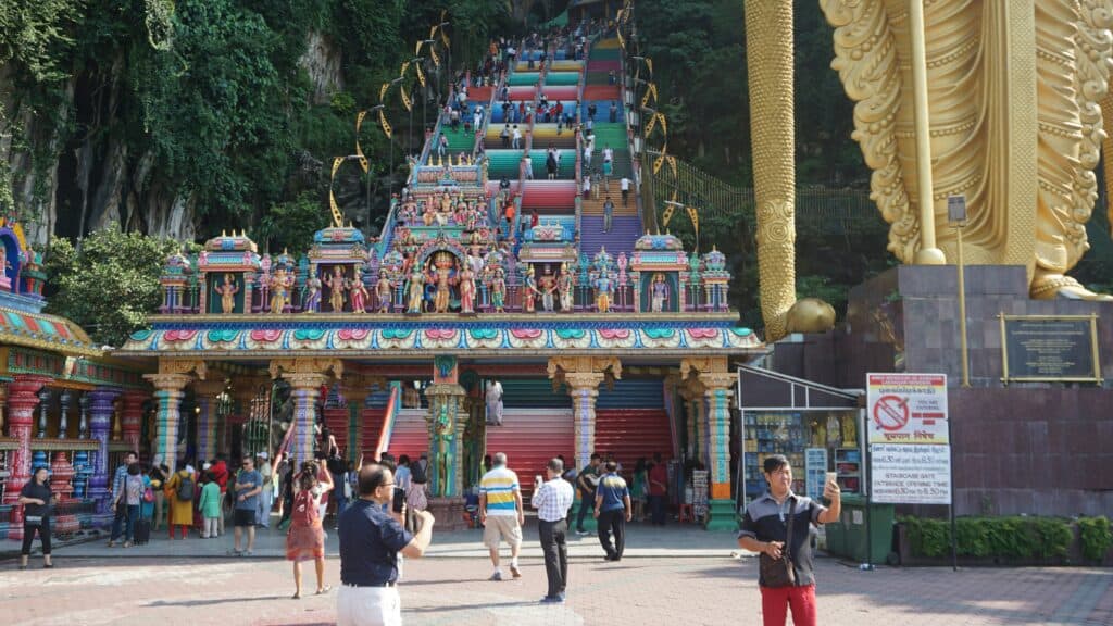 Batu Caves Hindu temple entrance in Selangor, Malaysia, featuring colourful steps, ornate sculptures and the golden Lord Murugan statue.