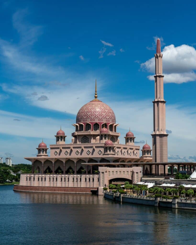 Putra Mosque in Putrajaya, Malaysia, featuring its pink dome and tall minaret overlooking the lake.