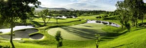 Panoramic view of Black Mountain Golf Club in Hua Hin, Thailand, featuring a lush putting green, sand bunkers, water hazards and mountain scenery.