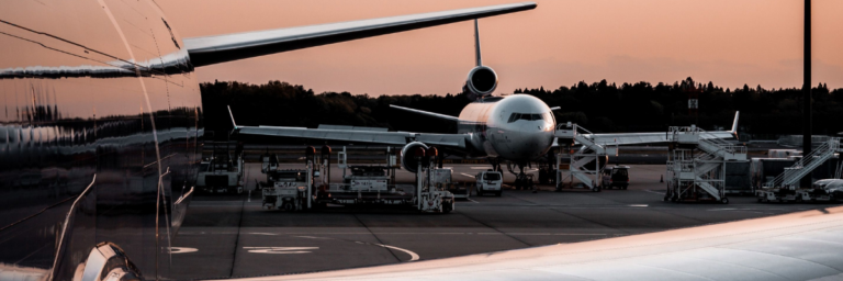 Two airplanes parked on a tarmac during sunset, showing airport operations.