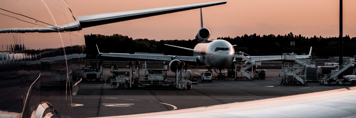 Two airplanes parked on a tarmac during sunset, showing airport operations.