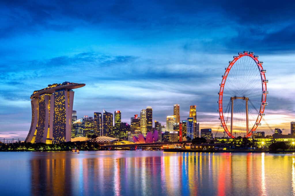 Singapore skyline at twilight, featuring Marina Bay Sands, the illuminated Singapore Flyer and colourful reflections across Marina Bay.