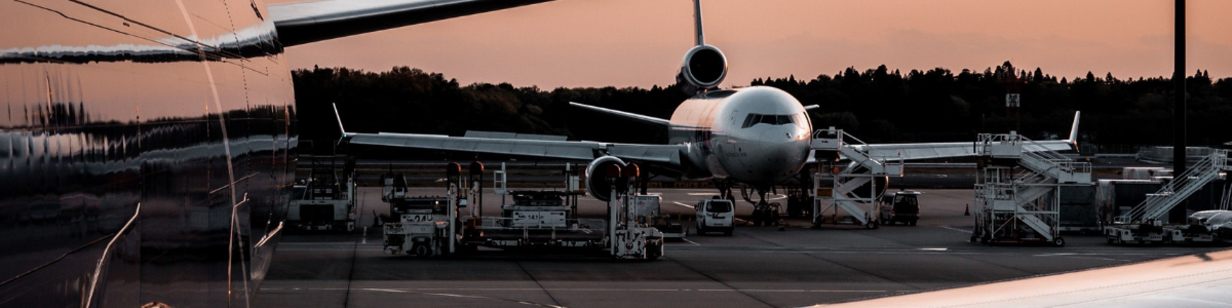 Two airplanes parked on a tarmac during sunset, showing airport operations.